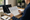 Person reviews a printed document beside an open laptop at a desk in a home office.