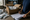 A person in navy scrubs records packaged supplies beside an open cardboard box.