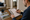 Man reviews property photos and writes on a clipboard at a wooden table in a home.