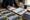 Person reviews property photographs and documents while writing notes at a desk with coffee nearby.