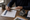 Person reviewing a checklist beside a house model, notebooks, and coffee on a wooden desk.