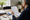 Person reviews a document at a desk with notebooks, folders, and a coffee mug nearby.