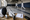 Fencers practice on indoor pistes while masks, protective gear, swords, and a scoring device rest on a nearby table.