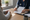 Healthcare professional reviews a printed chart with a seated person at a desk, with a stethoscope and coffee mug nearby.