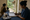 A healthcare worker records notes beside a tray of medicines as a woman and child wait.
