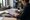 Woman reviews a printed document and writes notes at a desk in a home office.