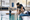 Swim instructor kneels beside a child practicing in an indoor pool.