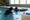 An adult supports a child holding the pool edge during an indoor swimming session.
