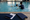 An instructor guides a child through an indoor pool exercise using blue flotation aids.