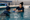 Swim instructor demonstrates a floating technique to a young swimmer in an indoor pool.