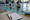 Instructor gestures while speaking with a child in an indoor pool beside a clipboard and pen.