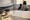 Adult and child sit together in a medical exam room beside an examination table, with paperwork and stethoscope foreground.