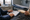 Two people sit across a desk as one reviews paperwork in a medical examination room.