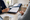 A person wearing a stethoscope reviews paperwork with another person at a consultation desk.