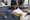 An adult and child sit in an exam room while a clinician reviews paperwork beside a stethoscope.