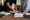 Two people review paperwork at a wooden table, with one pointing to a document.