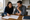 Two people review paperwork together at a kitchen table, with notebooks and a mug nearby.