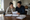 Couple reviewing paperwork together at a kitchen table, with folders, notebooks, and a pen nearby.