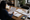 Woman reviews printed documents at a wooden desk in an office with notebooks and coffee.