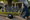 Person kneels beside a lawn assembling a 2025 graduation display with balloons, stars, and tools.