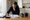 Woman reviews paperwork at a table beside a miniature house, calculator, and coffee mug.
