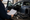 Person reviews a document beside an open car, with speakers and audio components arranged on a workbench.