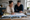 Couple reviews new home construction photos and paperwork at a kitchen table.