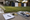 Blank yard signs stand on a lawn beside a sprinkler, clipboard, measuring tape, and sign-making materials.