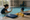 An adult raises a hand toward a child in an indoor pool during instruction.
