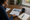 Person reviews a document featuring a house photo at a wooden desk with coffee and notebook.