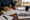 Person marks a location on a map beside housing brochures and paperwork at a desk.