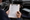 Person checks a clipboard checklist beside a loose car radio inside a vehicle.