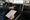 Person points to a car’s dashboard touchscreen while holding a checklist inside a vehicle.