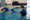 An instructor supports a child practicing swimming in an indoor pool during a one-on-one lesson.
