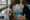 Swim instructor shows a child illustrated communication cards beside an indoor pool.