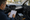 Man writes on a clipboard inside a car beside a removed audio unit and exposed door speaker.