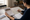 Woman reviews a map and house plans at a table, pointing to a location with a pen.
