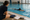 Swim instructor watches a swimmer practice with a kickboard in an indoor pool.