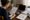Woman reviews a checklist and sketches at a table beside a laptop, baby blanket, and stuffed toys.