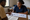 Healthcare worker discusses illustrated cards with a seated man at a table in a clinic room.