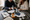 Two adults assemble paper stork sign pieces at a table, surrounded by stars, hearts, clouds, and craft supplies.