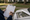 Person reviews a property plan on a clipboard beside an aerial yard layout, with a suburban home in the background.