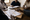 A group of people review documents and take notes around a wooden table in a modest office.