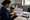Woman in a clinic examines an illustrated medical form while writing beside a tray of supplies.