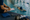 Person writes on a clipboard beside a swimmer practicing with a kickboard in an indoor pool.
