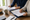 Two adults review paperwork together at a dining table with folders, coffee, and a notepad.