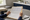 Person reviews an open binder of tabular forms at a desk beside papers and a mug.