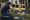 Person arranging colorful star, balloon, gift, and other yard decorations on a lawn beside a house.