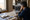 A man examines maps and home photographs at a dining table beside a coffee mug.