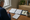 Person reviews handwritten notes and open documents at a desk beside coffee and a window.